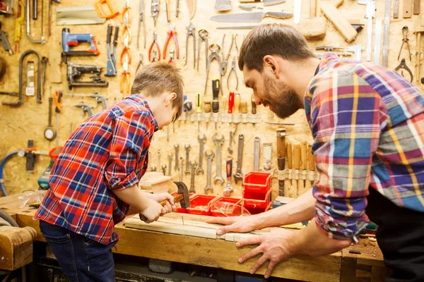 Pai e filho com martelo trabalhando na oficina — Fotografia de Stock