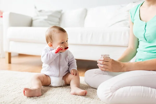 Mother and baby with spoon eating puree at home — Stock Photo, Image