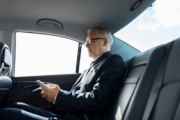 Sénior hombre de negocios mensajes de texto en el teléfono inteligente en coche —  Fotos de Stock