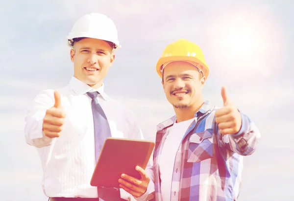 Lächelnde Bauarbeiter in Harthüten mit Tablet-PC — Stockfoto