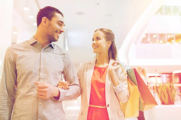 Feliz jovem casal com sacos de compras no shopping — Fotografia de Stock