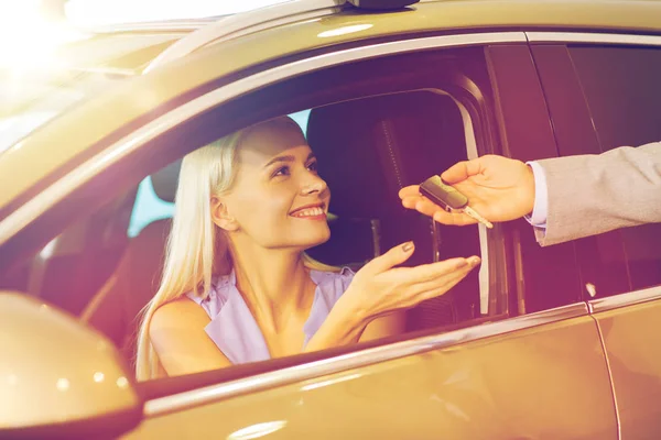 Mujer feliz consiguiendo la llave del coche en demostración auto o salón — Foto de Stock