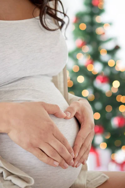 Primer plano de la mujer embarazada haciendo gesto del corazón — Foto de Stock