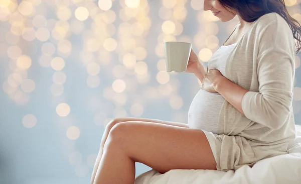 Primo piano della donna incinta con tazza di tè a letto — Foto Stock