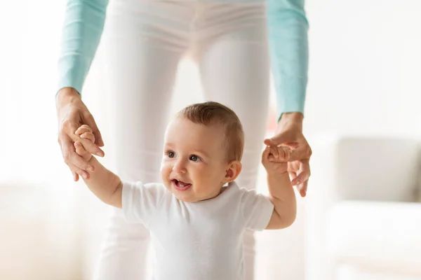 Bebé feliz aprender a caminar con la ayuda de la madre — Foto de Stock