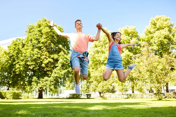 Glad tonåring par hoppar på sommaren park — Stockfoto