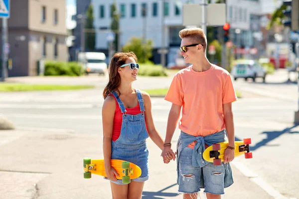 10代のカップルがスケートボードを持って街を — ストック写真