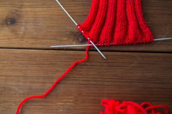 Hand-knitted item with knitting needles on wood — Stock Photo, Image