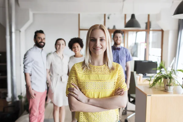 Gelukkig jong vrouw over creatief team in kantoor — Stockfoto