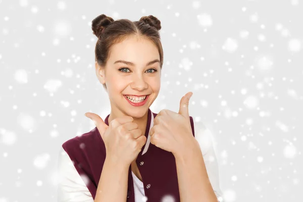 Happy teenage girl showing thumbs up over snow — Stock Photo, Image