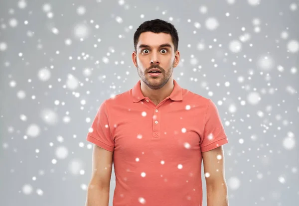 Удивленный мужчина в футболке с поло на снежном фоне — стоковое фото