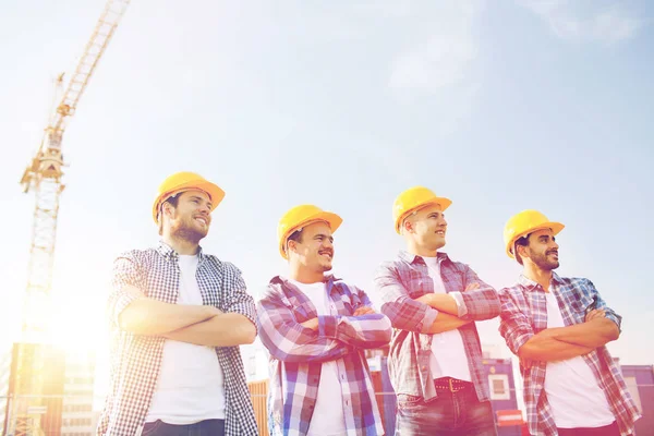 Grupp av leende byggare i hardhats utomhus — Stockfoto