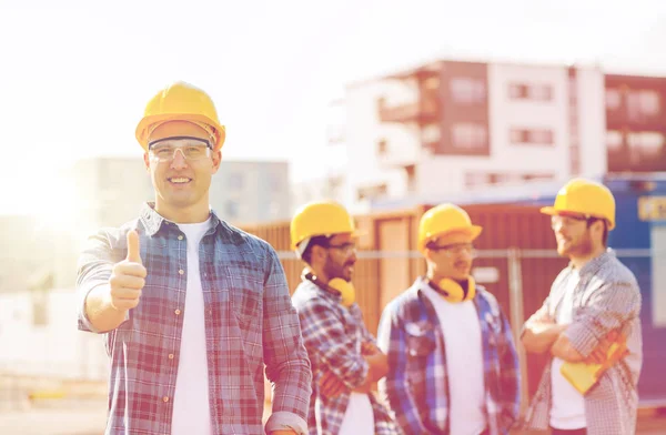 Grupo de construtores sorridentes em hardhats ao ar livre — Fotografia de Stock