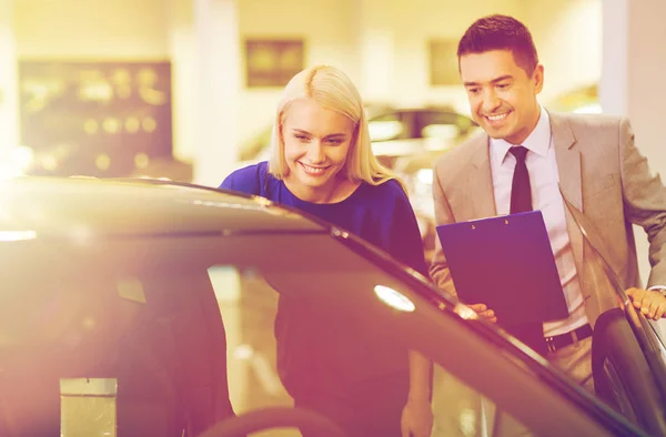 Mulher feliz com negociante de carro em auto show ou salão de beleza — Fotografia de Stock