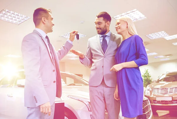 Casal feliz com revendedor de carro em auto show ou salão — Fotografia de Stock