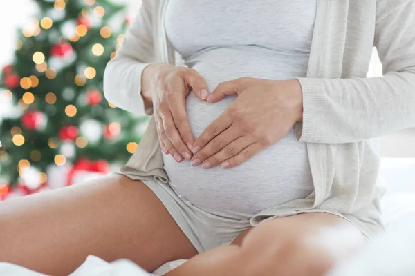 Primer plano de la mujer embarazada haciendo gesto del corazón — Foto de Stock