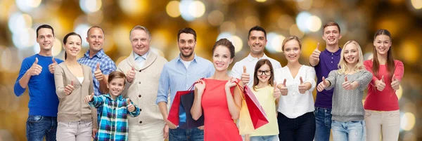 Happy people with shopping bags showing thumbs up — Stock Photo, Image
