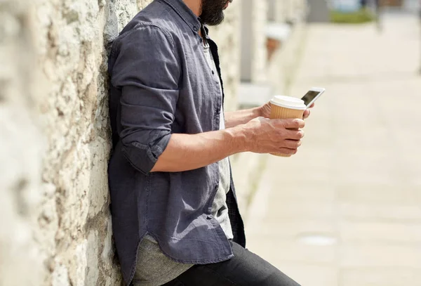 街でコーヒーを飲みながらスマート フォンを持つ男 — ストック写真