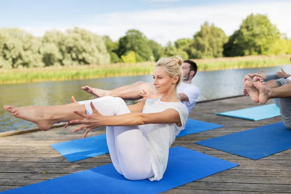 Pessoas fazendo ioga em meia-barco posar ao ar livre — Fotografia de Stock