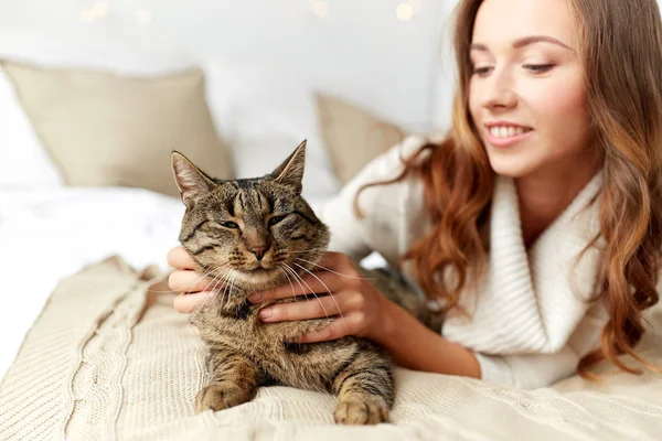 Glad ung kvinna med katt i sängen hemma — Stockfoto