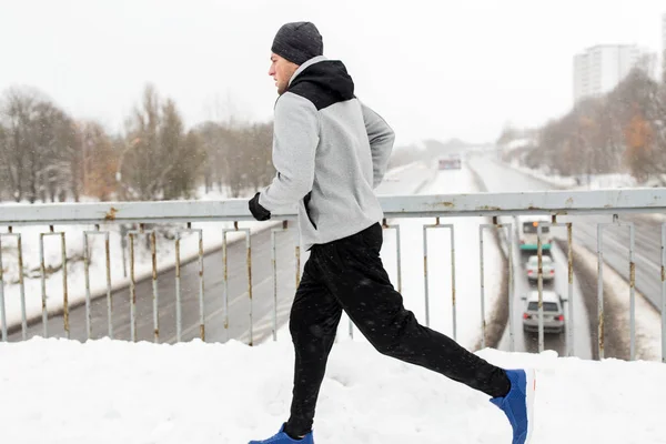 Человек бежит по заснеженной дороге зимнего моста — стоковое фото