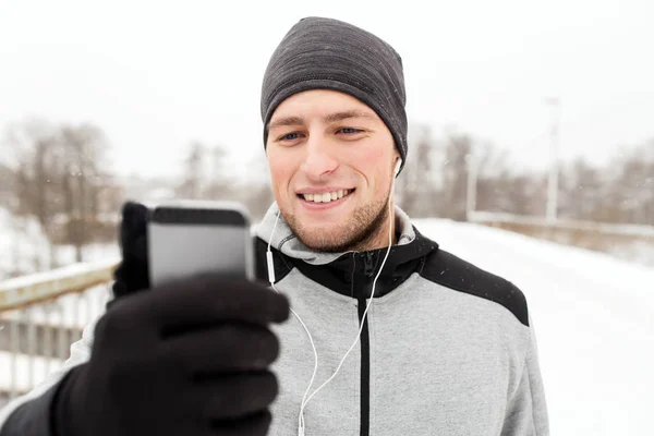 Boldog ember, fülhallgató és smartphone télen — Stock Fotó
