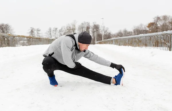 Человек упражнения и растяжения ноги на зимнем мосту — стоковое фото