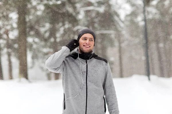 Homem de esportes feliz com fones de ouvido na floresta de inverno — Fotografia de Stock