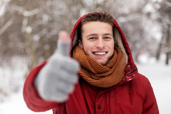 Lycklig man i vinterjacka visar tummen — Stockfoto