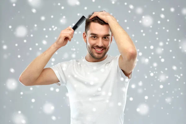 Hombre feliz cepillando el cabello con peine sobre la nieve —  Fotos de Stock