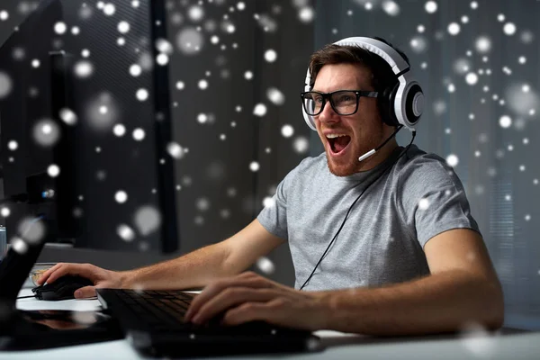 Hombre en auriculares jugando videojuego de ordenador en casa —  Fotos de Stock