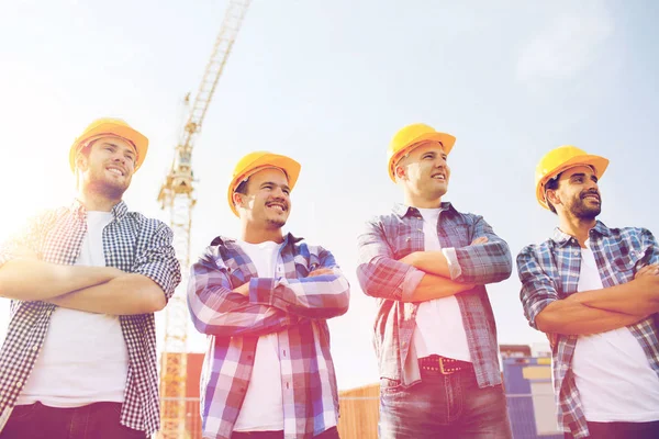 Group of smiling builders in hardhats outdoors — Stock Photo, Image
