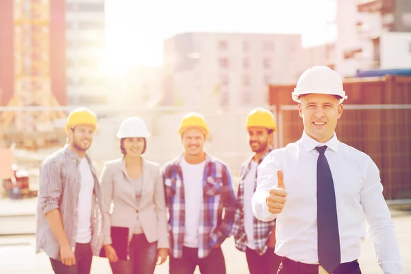 Grupo de construtores sorridentes em hardhats ao ar livre — Fotografia de Stock