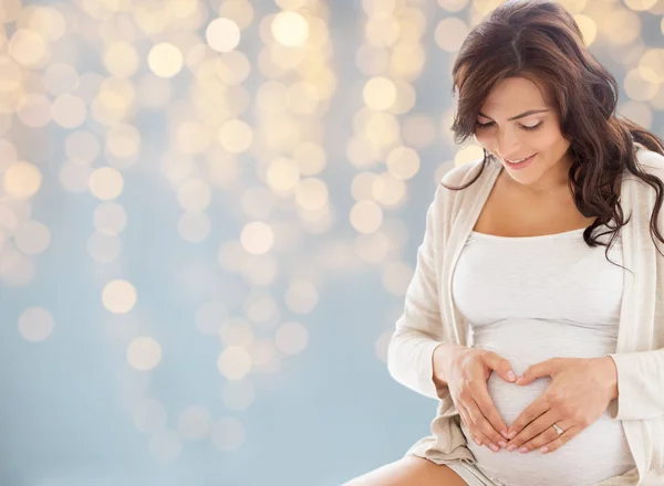 Glad gravid kvinna gör hjärtat gest i sängen — Stockfoto