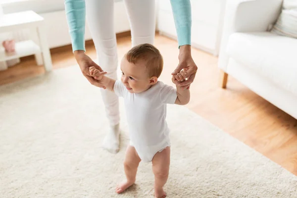 Happy baby leren lopen met hulp van de moeder — Stockfoto