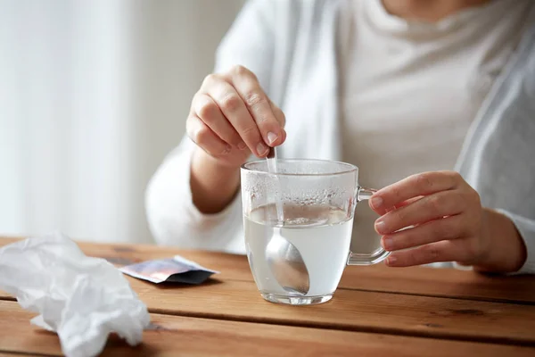 Woman stirring medication in cup with spoon — Stock Photo, Image