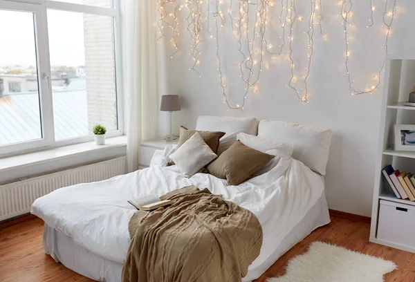 Dormitorio con cama y guirnalda de Navidad en casa — Foto de Stock