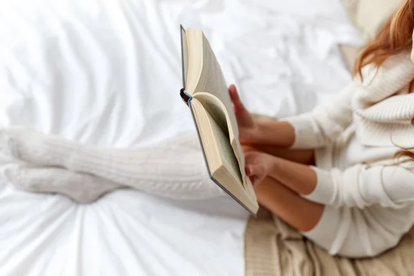 Close up of young woman reading book in bed — Stock Photo, Image