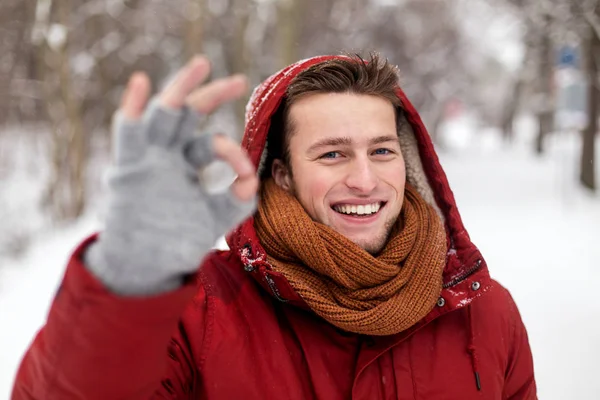 Счастливый человек в зимней куртке, показывающий знак ладони — стоковое фото