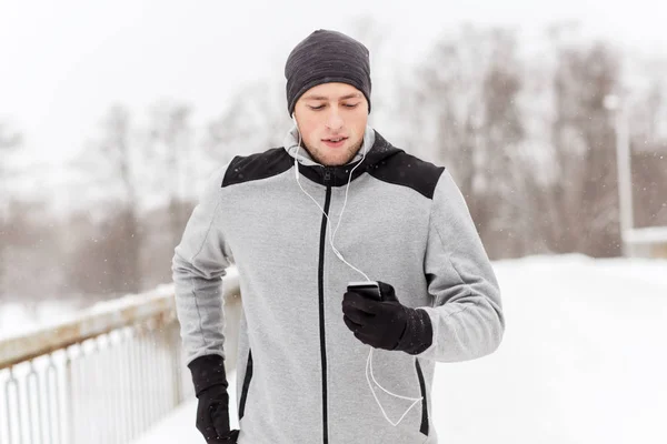 Szczęśliwy człowiek z słuchawki i smartfon w zimie — Zdjęcie stockowe