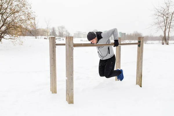 Young man exercising on parallel bars in winter — Stock Photo, Image