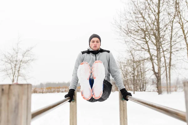 Jovem exercitando-se em barras paralelas no inverno — Fotografia de Stock