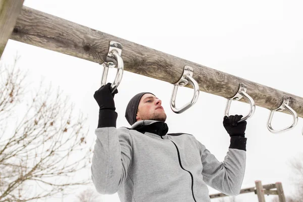 Jovem exercitando-se na barra horizontal no inverno — Fotografia de Stock