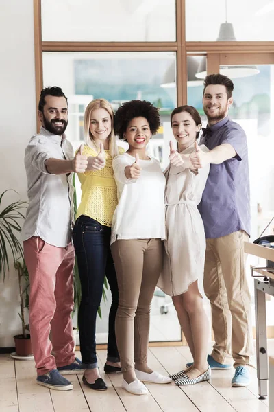 Feliz equipe criativa mostrando polegares no escritório — Fotografia de Stock