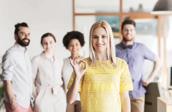 Feliz mujer mostrando ok sobre creativo oficina equipo — Foto de Stock