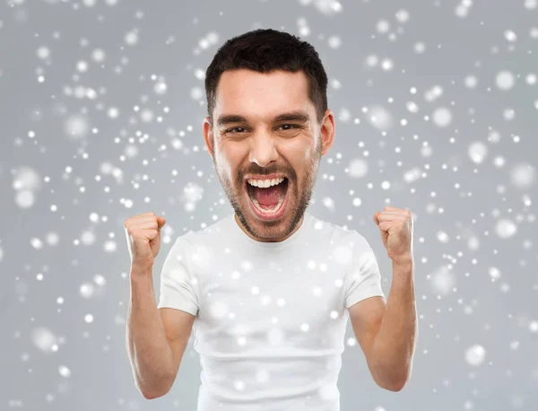 Arrabbiato giovane uomo che celebra la vittoria sulla neve — Foto Stock