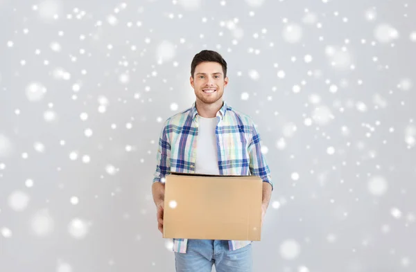 Sonriente joven con caja de cartón en casa — Foto de Stock