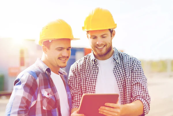 Construtores sorridentes em hardhats com tablet pc — Fotografia de Stock