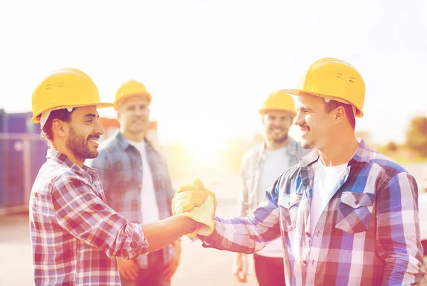 Grupo de construtores sorridentes apertando as mãos ao ar livre — Fotografia de Stock