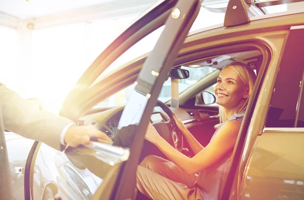 Happy woman with car dealer in auto show or salon — Stock Photo, Image